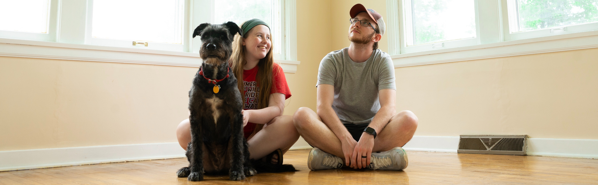 Young couple with dog sitting in unfurnished room