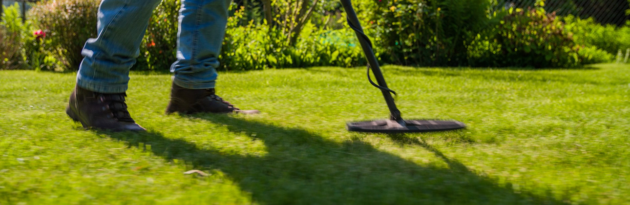 Close-up of person using metal detector in grass